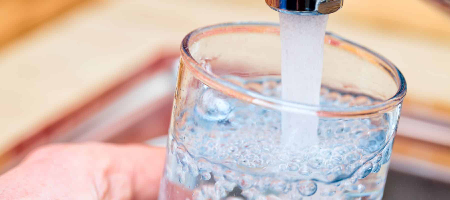 A close-up of water being poured into a glass from a kitchen tap